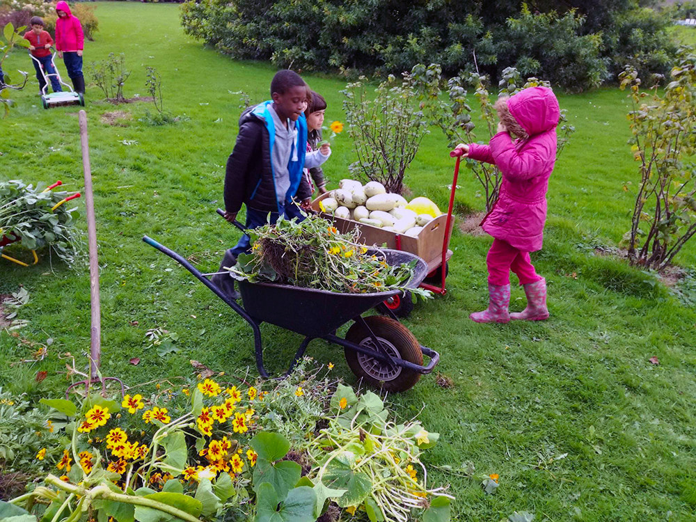 enfants qui jardinent avec une brouette en avant-plan